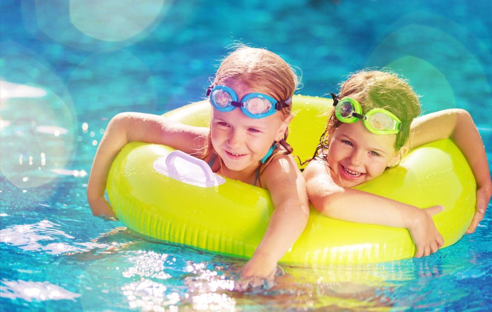 Zwei fröhliche Kinder mit Schwimmring im Badesee Coswig